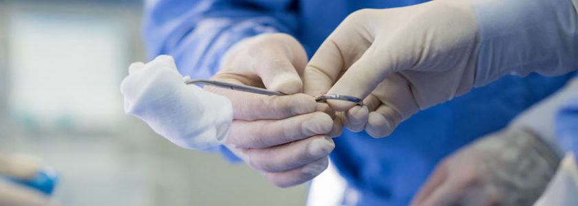 77149058 - detail of assistant passing surgical equipment to surgeon hand with protective glove. surgeon hand holding surgical tweezers. closeup of surgeons hands holding surgical scissors with sterilzed gauze.